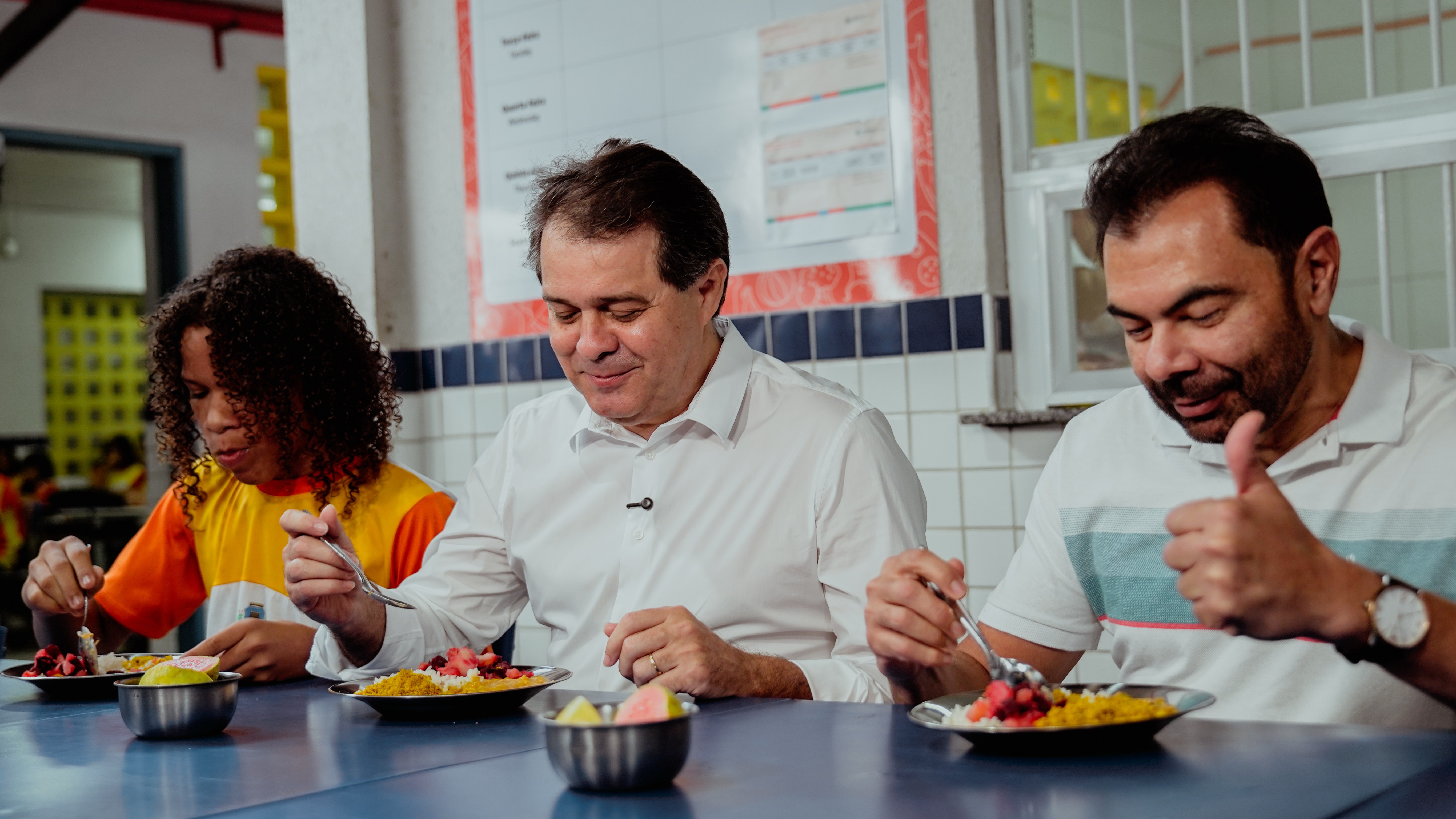 um aluno, prefeito evandro e secretário idilvan comendo o pratinho no refeitório da escola